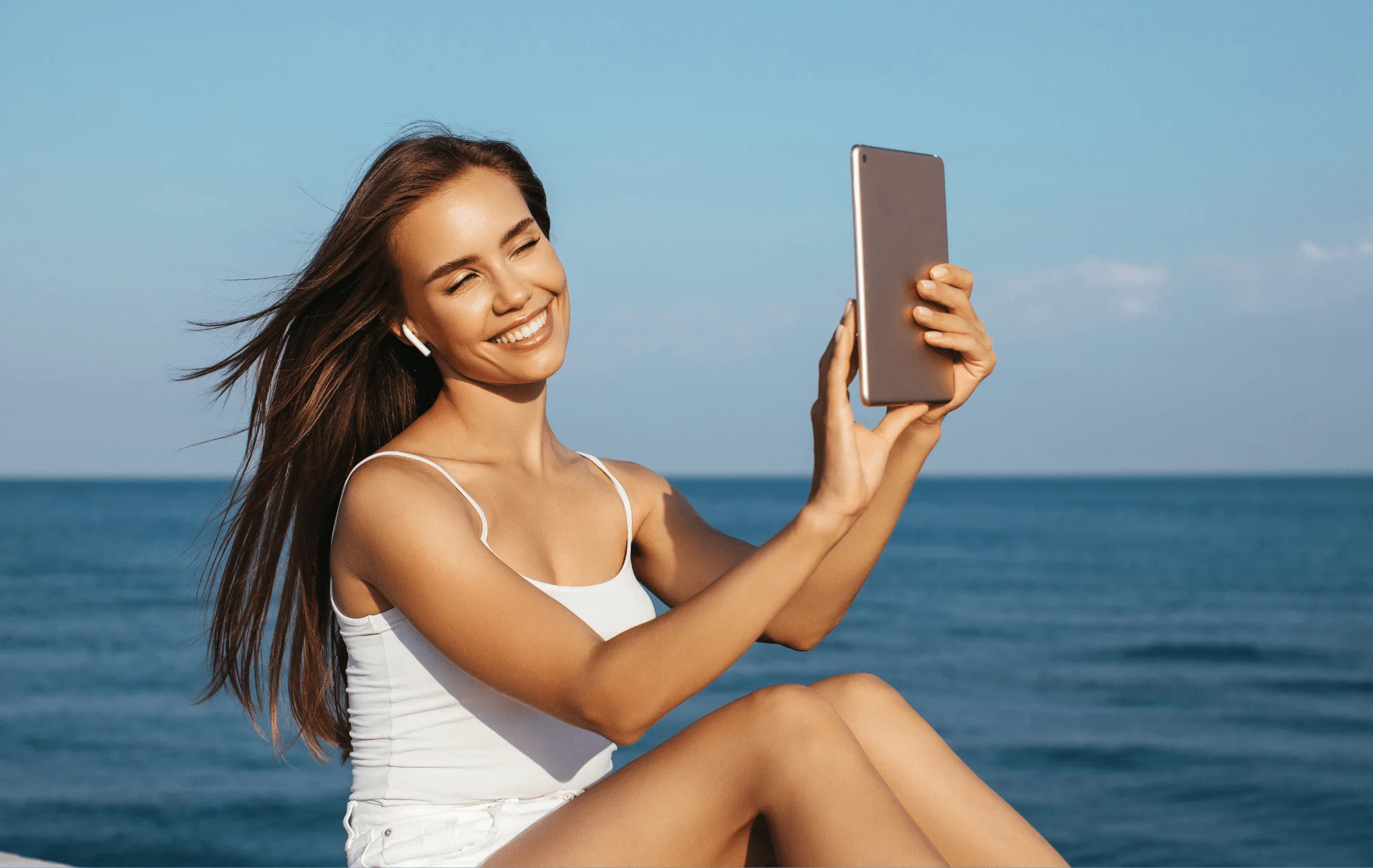 Woman using a mobile phone beside the ocean